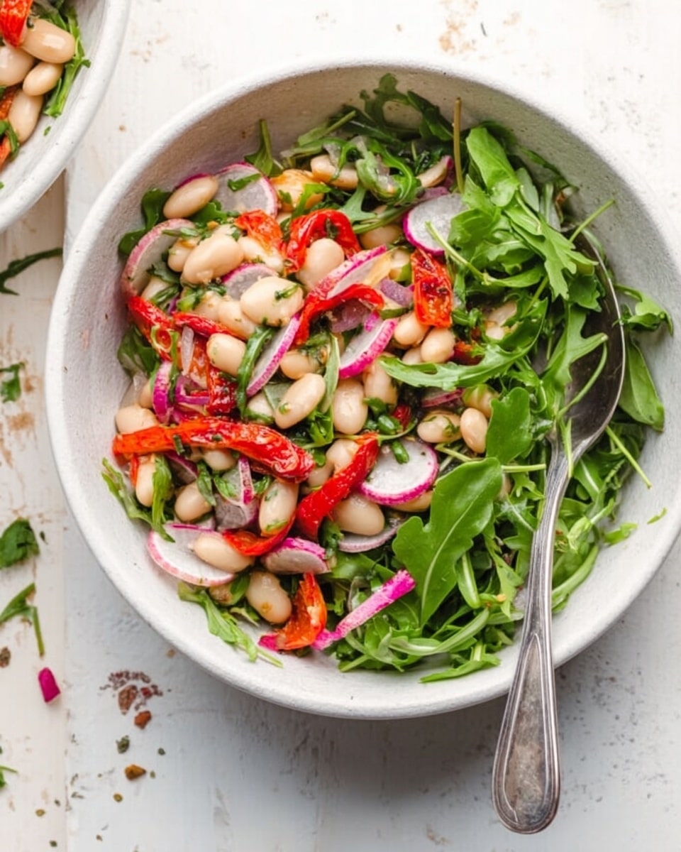 A white bowl filled with a bean salad that has three main layers: the first layer is large, smooth white beans; mixed evenly on top are halved red and yellow cherry tomatoes with shiny skin; scattered throughout are finely chopped green herbs and small white cheese chunks, creating a fresh and colorful texture. In the background, there is a white marbled surface with a blue cloth and a white bowl of green spinach leaves partially visible. Photo taken with an iphone --ar 4:5 --v 7