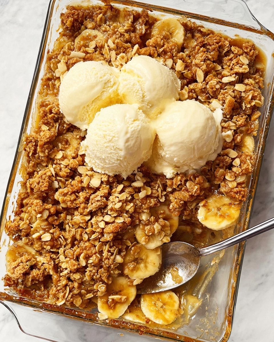 A white bowl holds a warm dessert with three main layers. The bottom layer is soft, cooked apple slices coated in a shiny brown cinnamon sauce. On top of that is a crunchy, coarse crumb topping with small nut bits that look golden brown and slightly sticky. The last layer is a creamy, pale yellow scoop of vanilla ice cream melting slightly over the warm dessert. A silver spoon is inserted into the bowl from the right side, ready to scoop. The bowl sits on a white marbled surface, with another bowl and a clear glass baking dish in the background. Photo taken with an iphone --ar 4:5 --v 7