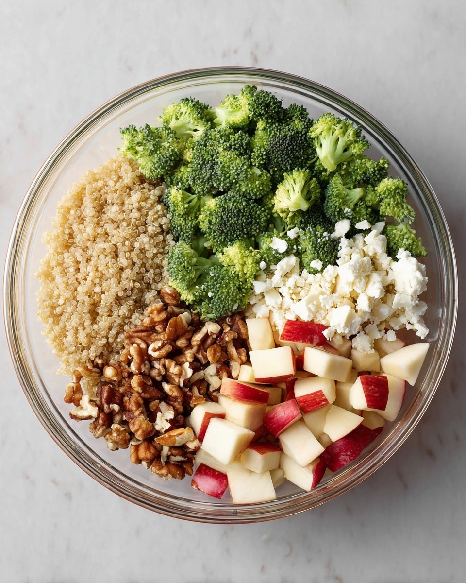 A close-up view of a quinoa salad in a white bowl filled with three main visible layers: the base layer of small, round, off-white quinoa grains scattered evenly, the middle layer made up of vibrant green broccoli florets and chopped mixed bell peppers in red, yellow, and orange pieces, and the top layer sprinkled with chopped almonds and finely chopped purple cabbage with bits of parsley leaves adding more green scattered throughout. A wooden spoon with a smooth grain pattern rests partly inside the bowl, touching the salad. The bowl sits on a clean white marbled surface. photo taken with an iphone --ar 4:5 --v 7
