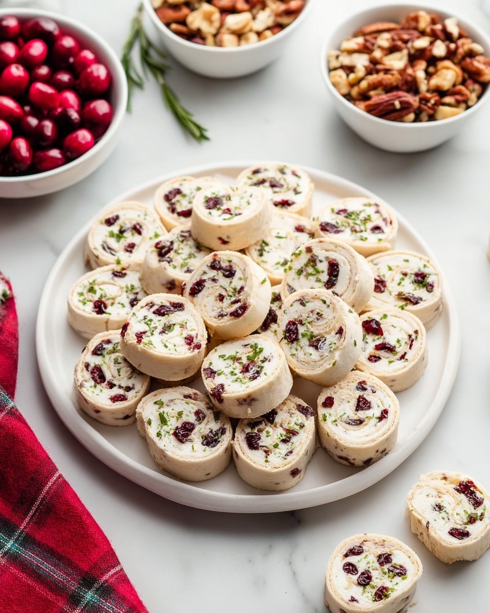 The image shows seven cream cheese and cranberry pinwheel rolls arranged in a slight curve on a white rectangular plate. Each roll has a soft, light cream-colored outer layer with a creamy white filling dotted with dark red cranberries and small green rosemary leaves layered evenly throughout. A silver butter knife with textured edges rests diagonally on the top left corner of the plate, with a spread of creamy white cheese on its blade. Around the plate, there are scattered dark red cranberries and a rosemary sprig on a white marbled textured surface. In the top left corner, some red berries on brown stems add a decorative touch. photo taken with an iphone --ar 4:5 --v 7