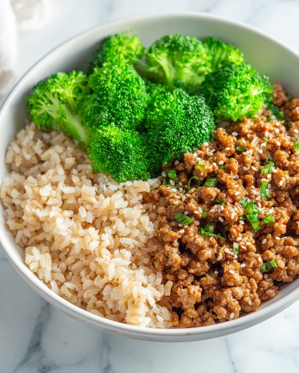 A white bowl contains three main layers: at the bottom is a layer of light brown cooked rice, above it sits a thick layer of minced meat mixed with small bits of mushroom, all coated in a light brown sauce and sprinkled with white sesame seeds and sliced green onions, on one side of the bowl is a layer of bright green steamed broccoli florets. The bowl is placed on a white marbled surface, with a white napkin and wooden chopsticks resting nearby, and lime wedges and cilantro to the side in the background. Photo taken with an iphone --ar 4:5 --v 7