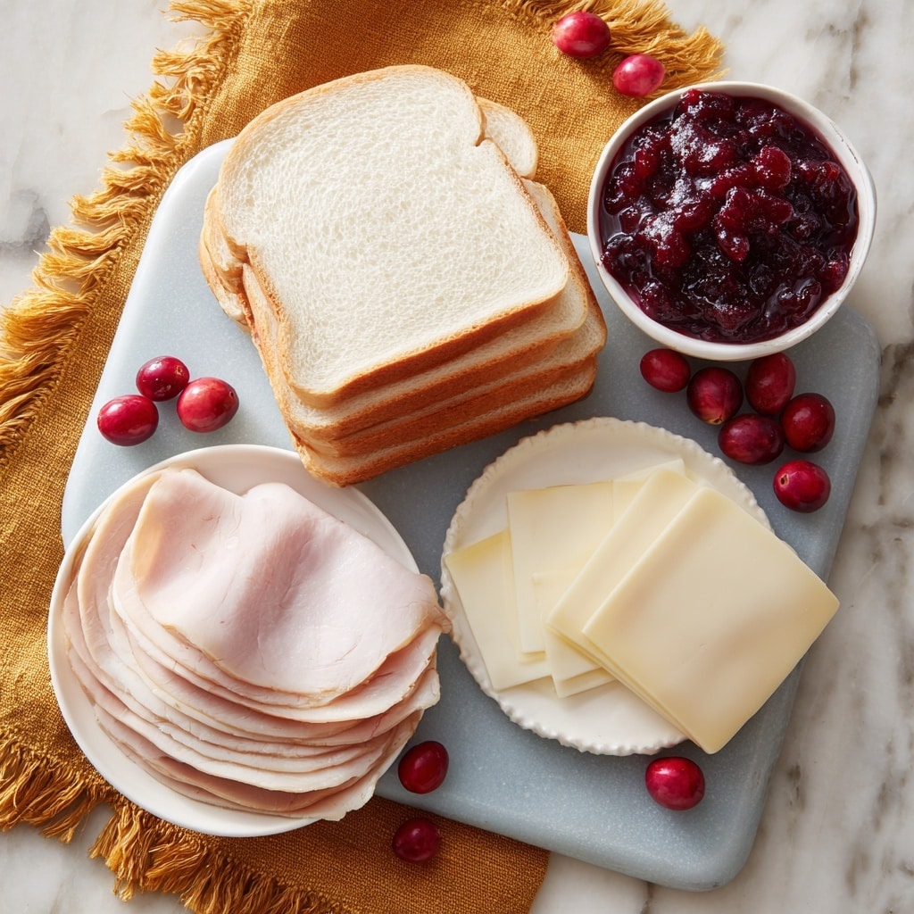 The image shows a sandwich preparation scene on a white marbled textured surface. At the center is a light blue cutting board holding several slices of white bread stacked at the top. On the left side of the board is a white plate with several thin slices of pale pink turkey meat layered unevenly. To the right of the turkey, there are four round slices of off-white cheese stacked neatly. Off to the top right corner, there is a white bowl filled with dark red cranberry sauce dotted with whole cranberries. Scattered around the board and bowl are several fresh red cranberries, adding a bright pop of color. A mustard yellow fringed cloth is draped beneath the cutting board, enhancing the arrangement’s warm and inviting feel. Photo taken with an iphone --ar 4:5 --v 7