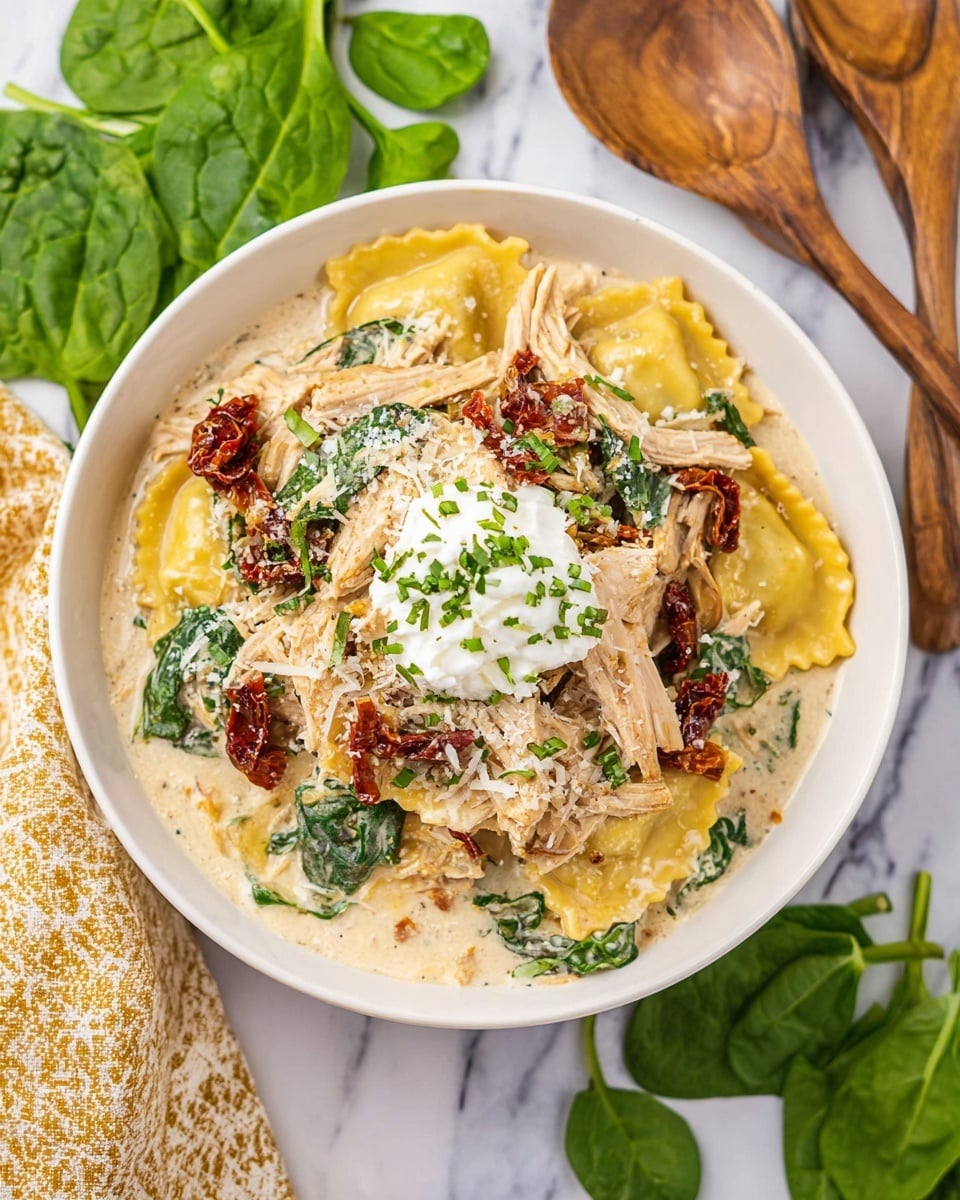 A white bowl filled with creamy soup layered with large yellow ravioli pieces, tender light brown chicken slices, dark green spinach leaves, and scattered sun-dried tomatoes with a deep reddish hue. The dish is topped with a dollop of white ricotta cheese sprinkled with chopped green herbs, and grated cheese dusted over the entire bowl. The bowl sits on a white marbled surface, next to fresh spinach leaves and a wooden spoon. photo taken with an iphone --ar 4:5 --v 7