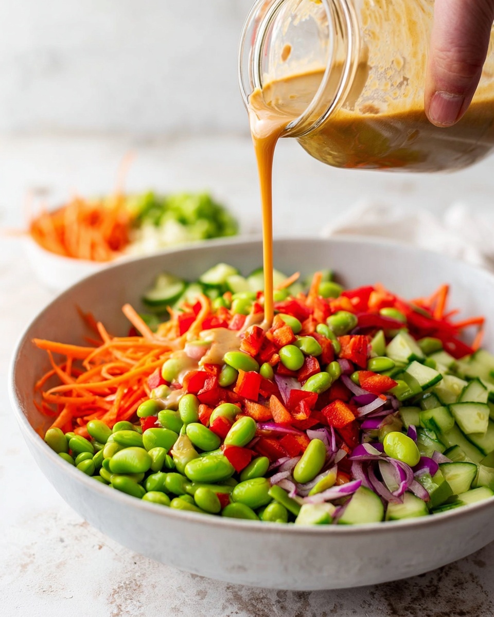 A white bowl filled with a colorful salad made of three main layers: bright green edamame beans, light beige chickpeas, and shiny red cherry tomatoes cut in halves. The salad is topped with thin sliced green herbs and sprinkled with white sesame seeds. Everything is lightly coated in a dark soy-based sauce that gives a glossy look. The bowl is placed on a white marbled surface. photo taken with an iphone --ar 4:5 --v 7