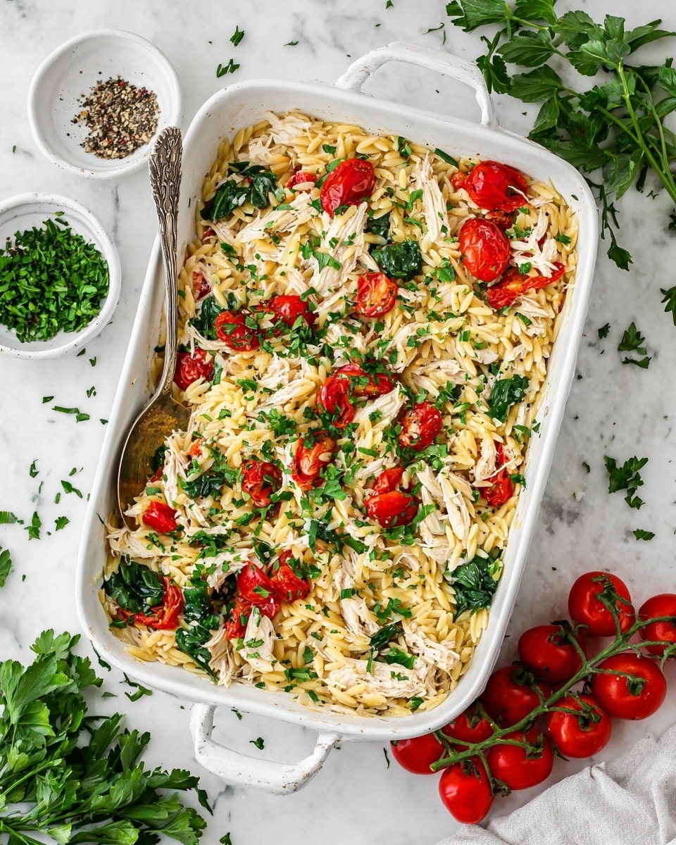 The image shows a white bowl filled with a colorful rice dish. At the bottom, there is a layer of light yellow rice mixed with small pieces of orange and green vegetables. On top of the rice, slices of grilled chicken with a brown, slightly charred surface are neatly arranged. The chicken is garnished with fresh green basil leaves. Around the chicken, there are whole roasted cherry tomatoes with a shiny red skin and some white creamy sauce drizzled lightly over the top. The bowl sits on a white marbled surface. photo taken with an iphone --ar 4:5 --v 7