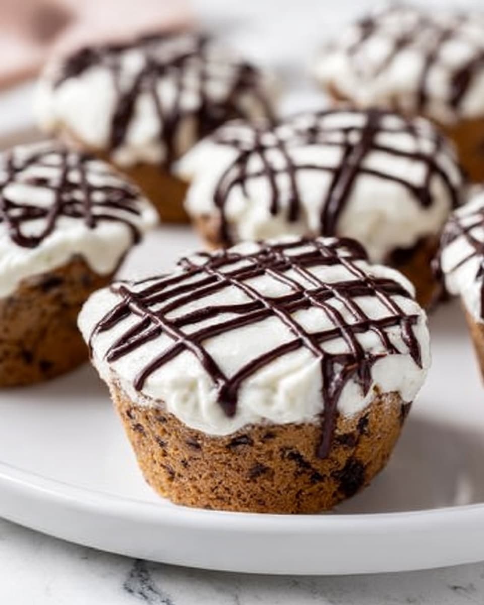The image shows a small round dessert that has three layers. The bottom layer is a thick, light brown cookie or cake base with a slightly crumbly texture. On top of this base is a thick, smooth white cream layer that looks soft and fluffy, with small peaks and swirls. The top layer is decorated with drizzles of dark chocolate that create thin, irregular lines over the white cream. The dessert is placed on a white plate which sits on a white marbled surface, and there are a few whole chocolate cookie pieces scattered around the plate. Photo taken with an iphone --ar 4:5 --v 7