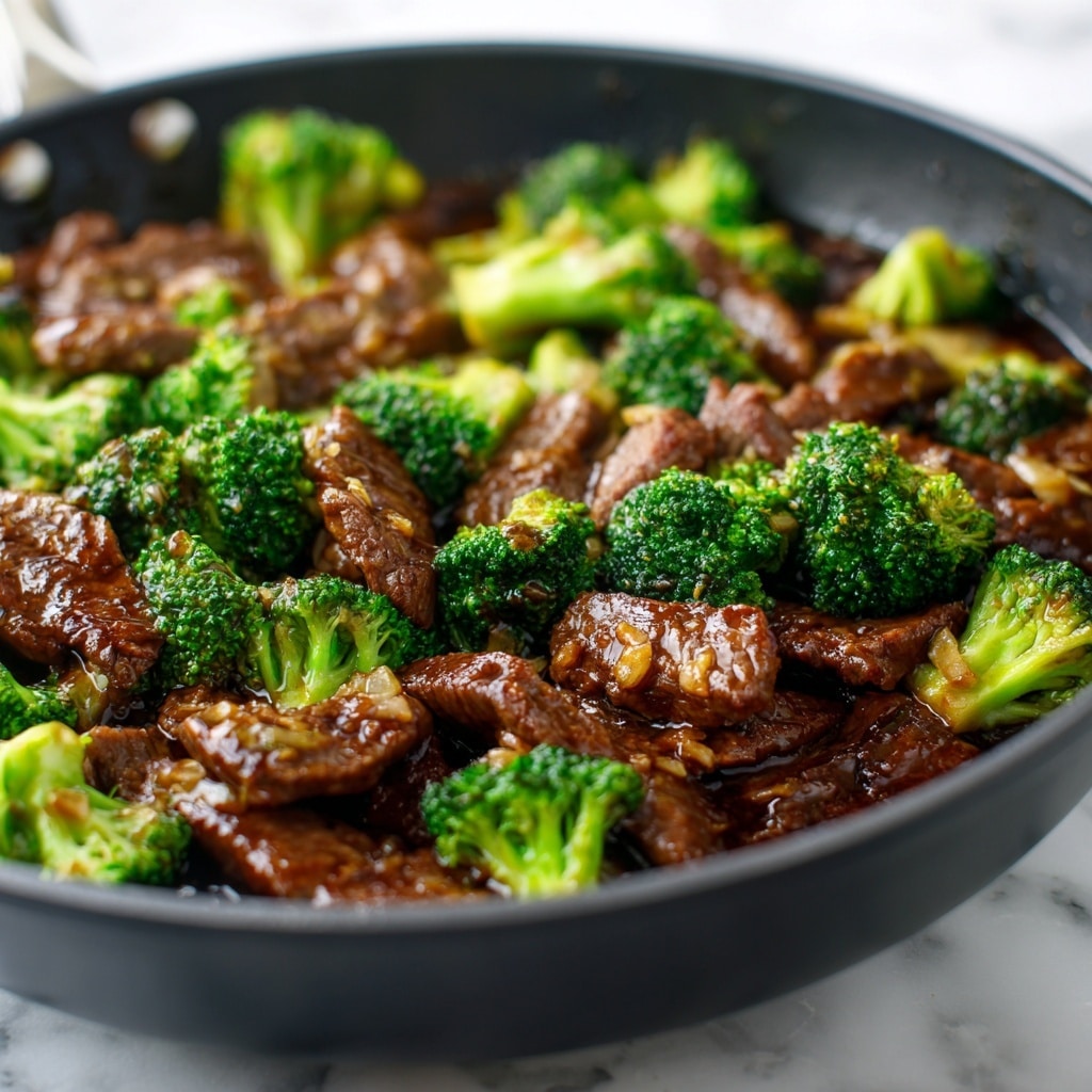 A rough-edged beige bowl filled with a base layer of white rice, on top of which is a thick layer of dark brown saucy beef mixed with bright green broccoli florets, the sauce shiny and coating the ingredients evenly. To the left of the bowl are wooden chopsticks resting on the edge, with a small white ceramic jar with blue flower patterns and a small wooden bowl with coarse salt and a wooden spoon beside it, all set on a white marbled surface. A dark grey cloth sits folded to the right side of the bowl. Photo taken with an iphone --ar 4:5 --v 7