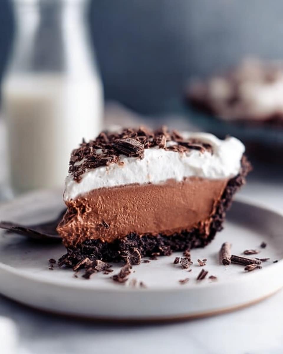 The image shows a close-up of a pie with three layers in a white pan. The bottom layer is dark brown and crumbly, the middle layer is smooth and milk chocolate colored, and the top layer is thick, white, and creamy. There are many dark chocolate curls scattered over the white layer. A slice of the pie is partly removed, showing the layers clearly. The pie sits on a white marbled surface. Photo taken with an iphone --ar 4:5 --v 7