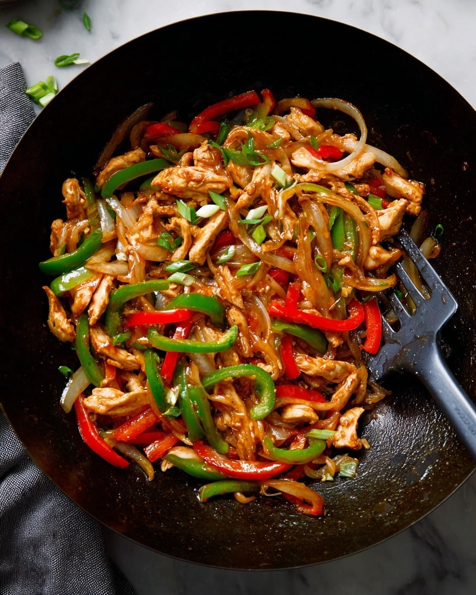 A black bowl filled with a stir-fry dish composed of layered ingredients including glossy cooked slices of light brown chicken on top, mixed with sautéed bell pepper strips in red and green, and translucent cooked onion slices that have a soft texture; scattered fresh green onion rings are placed on top and around the dish, adding a vibrant pop of color. The bowl sits on a dark cloth with some green onion pieces scattered around. The background is a white marbled surface with a few sesame seeds visible. photo taken with an iphone --ar 4:5 --v 7