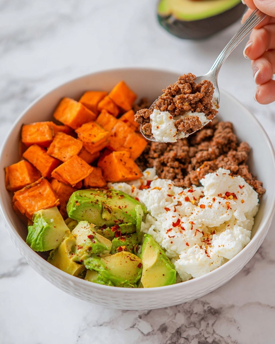 A white bowl with four main layers is shown on a white marbled surface. The first layer is cubed bright orange roasted sweet potatoes positioned in one section of the bowl. Next to it is a ground beef layer with a crumbly texture and brown color. Another section holds green chunks of avocado with a creamy, smooth look. The last part contains white cottage cheese with a soft, lumpy texture and is sprinkled with red pepper flakes. A spoon with a mix of avocado, cottage cheese, roasted sweet potatoes, and ground beef is held above the bowl by a woman's hand. Photo taken with an iphone --ar 4:5 --v 7
