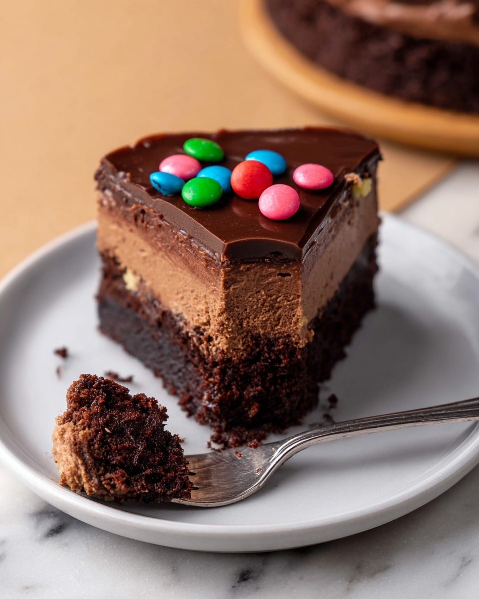 A two-layer round chocolate cake sits on a white plate with a piece of white parchment paper underneath. The bottom layer is dark brown and dense, while the top layer is a lighter brown with a smooth texture. The cake is covered with a glossy dark chocolate frosting spread evenly on top. Brightly colored small round sprinkles in various colors like pink, blue, green, yellow, orange, and black are scattered over the frosting, adding a festive look. The setting includes a white marbled surface underneath, with a small bowl of more colorful sprinkles nearby, and a striped cloth in the background. Photo taken with an iphone --ar 4:5 --v 7