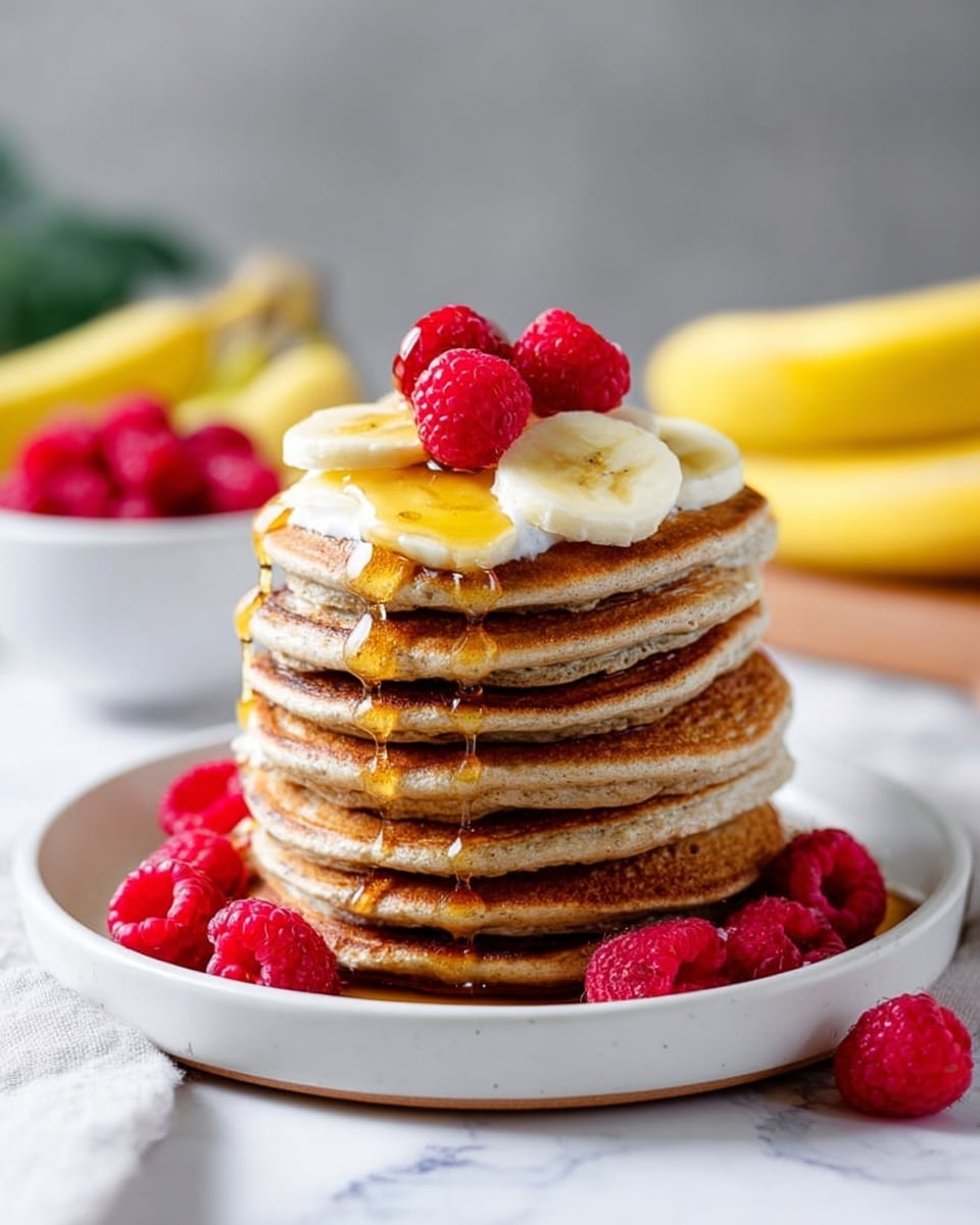 A tall stack of eight golden-brown pancakes sits on a white plate, each pancake fluffy with slightly crisp edges. On top, there is a layer of white cream, followed by thin, pale yellow banana slices and several bright red raspberries scattered. A thick stream of amber honey drips slowly down the sides of the stack. Extra raspberries surround the base of the stack on the white plate. The plate is placed on a white marbled surface with blurred bananas in the background and a white bowl filled with more raspberries just behind. Photo taken with an iphone --ar 4:5 --v 7